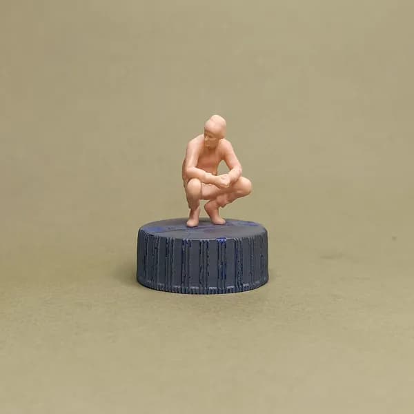 Мужчина сидит на корточках. Фигурка в масштабе 1:43.